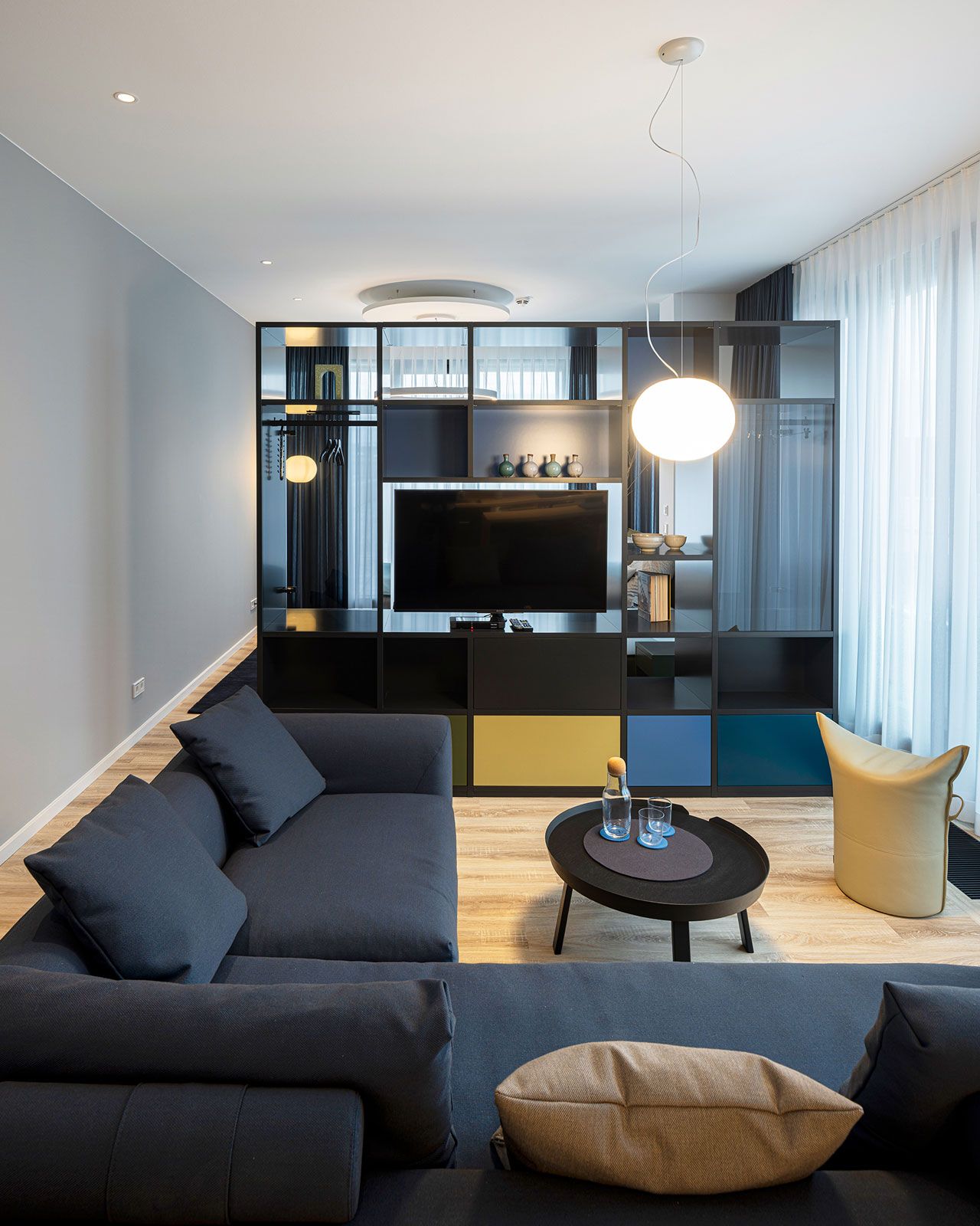 Büroetage und Firmenapartments in Hamburg - Das offene Regal dient als raffinierter Raumtrenner von Schlaf- und Wohnbereich.