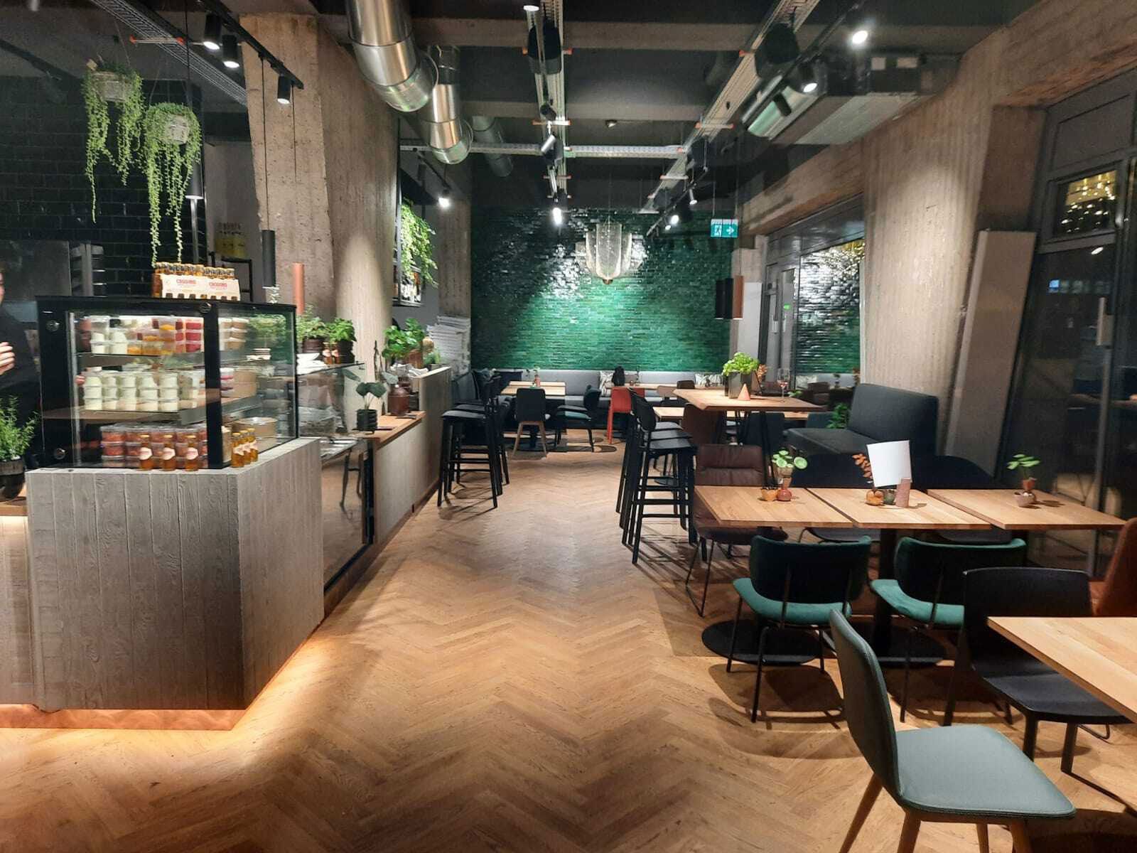 Familienrestaurant in Elmshorn - Blick in das Restaurant: Betonstützen und Lichtschienen schaffen einen modernen, industriellen Look. Die smaragdgrüne Fliesenwand dient als Eyecatcher des Einrichtungskonzeptes.