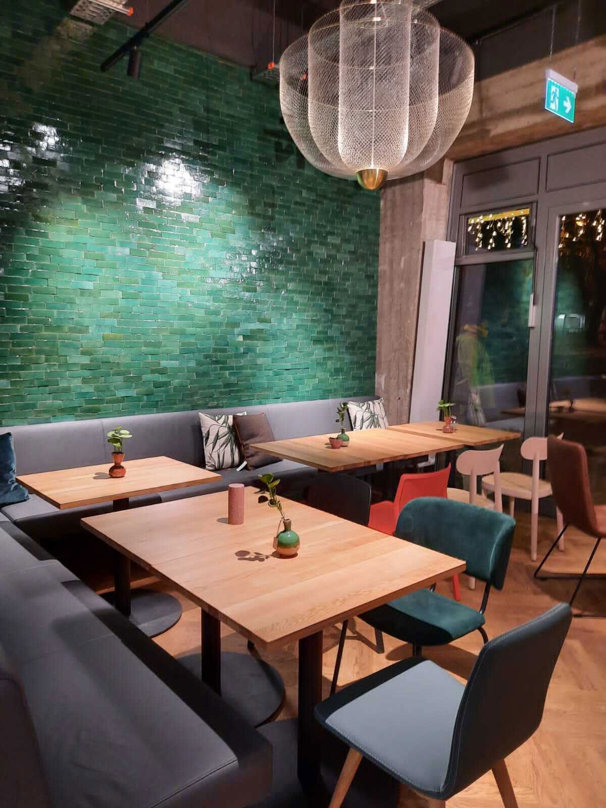 Familienrestaurant in Elmshorn - Modern inszenierter Kronleuchter setzt edlen Kontrast zur restlichen Einrichtung. Durch rote und grüne Farb-Highlights wird eine subtile Verbindung zur italienischen Küche geschaffen.