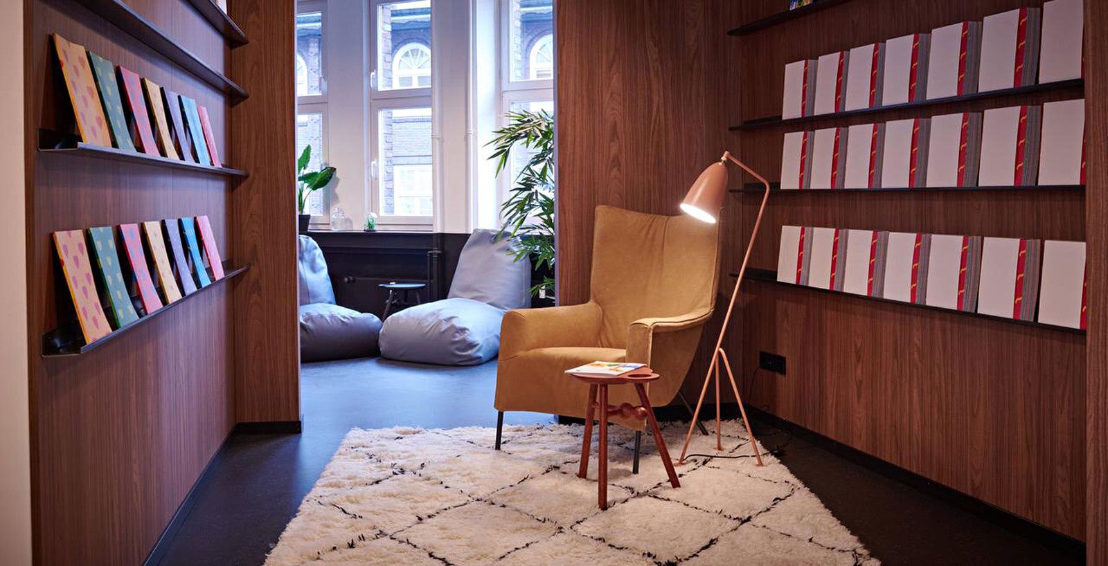 Education-Center in Hamburg - Beistellsessel von Pode, Stehleuchte Gräshoppa von Gubi, Beistelltisch Bottle Stool von Pode, Teppich von On The Rugs, Holzwände aus der Cramer Holzmanufaktur, Sitzsäcke Boya von Pode.