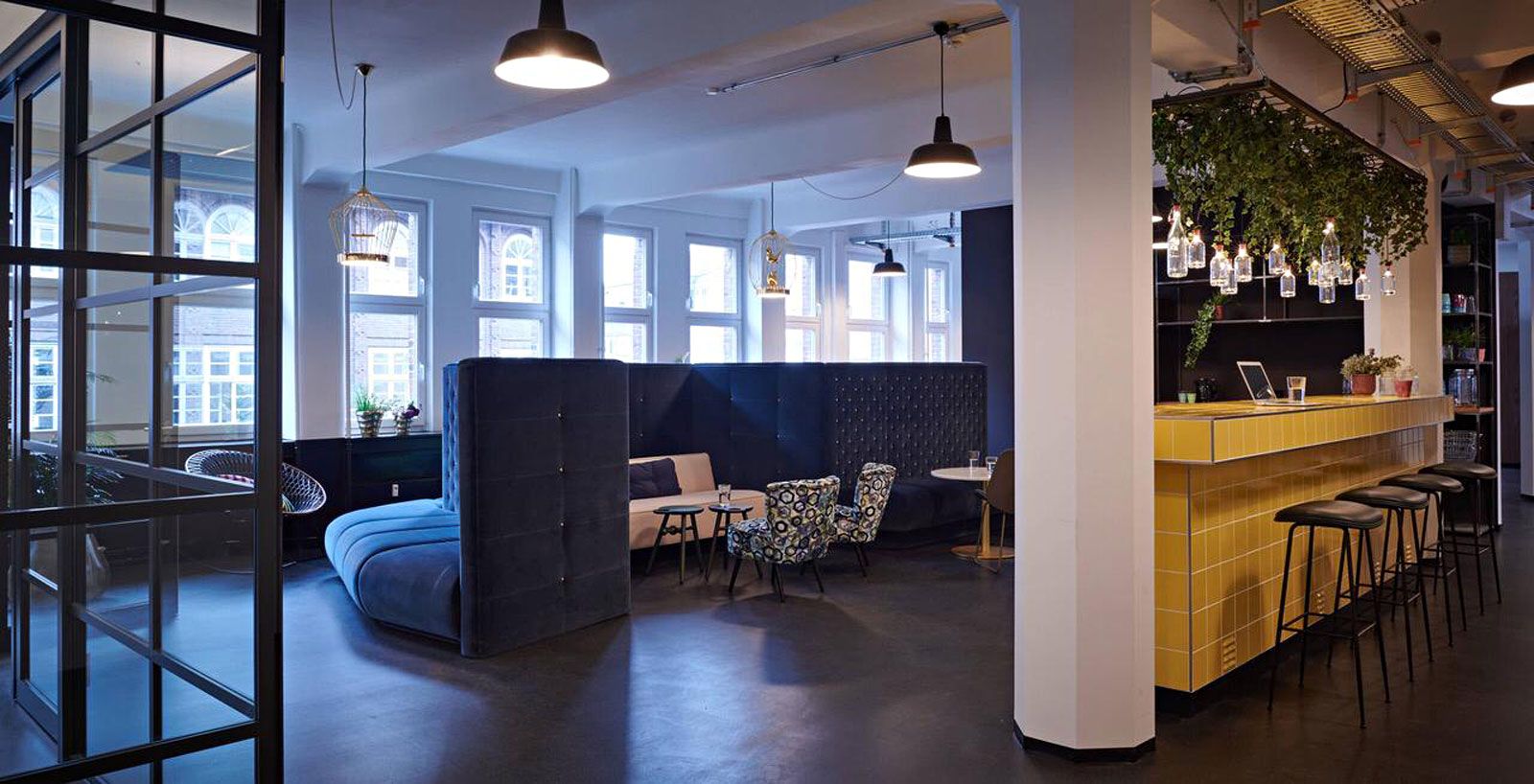 Education-Center in Hamburg - Bartresen aus der Cramer Holzmanufaktur mit Fliesen von Dtile, Barhocker Beetle von Gubi, Flaschenleuchten von Wever & Ducre, Lounge-Ecke aus der Cramer Polstermanufaktur (Design by Cramer Team), Vintage-Beistellsessel aus der Cramer Polstermanufaktur mit Stoff von Designers Guild, Beistelltische Bottle Stool von Pode, Sofa Modern Line von Gubi, Pendelleuchten von Bolichwerk.
