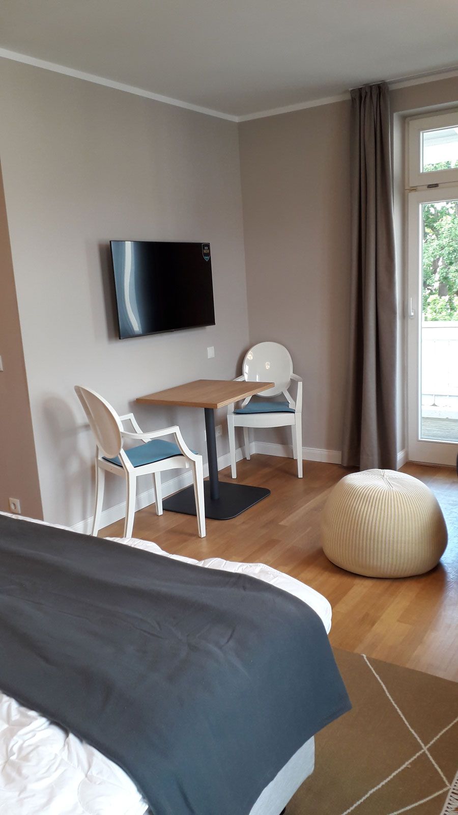 Ferienapartments in Binz - Louis Ghost Stühle von Kartell, Bistrotisch aus der Cramer Holzmanufaktur, Pala Hocker von Casalis, Fensterdekoration von JAB