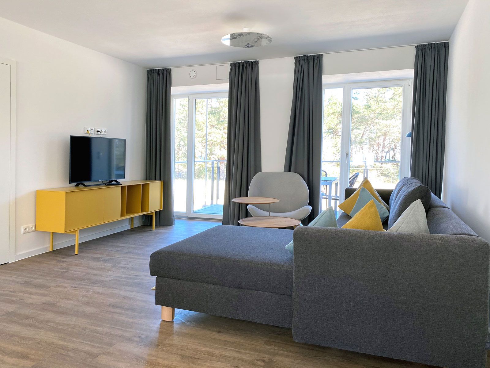 Ferienwohnungen in Prora - Vorhänge: Jab Anstoetz, Sofa: Franz Fertig, Dekokissen: Cramer Polstermanufaktur, Sessel: Softline, Beistelltische: Scholtissek, Sideobard: Novamobile, Deckenleuchte: Studio Italia