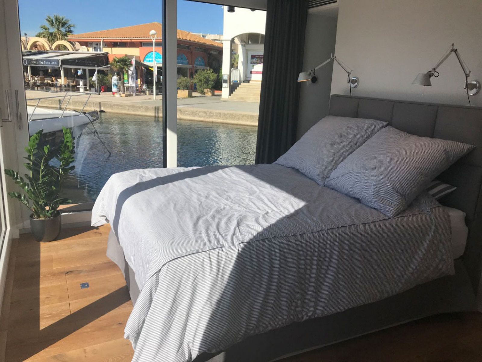 Hausboot in Cannes - Blick in die Schlafkabine Nr. 2: Bett aus der Cramer Polstermanufaktur, Wandleuchten Tolomeo von Artemide
