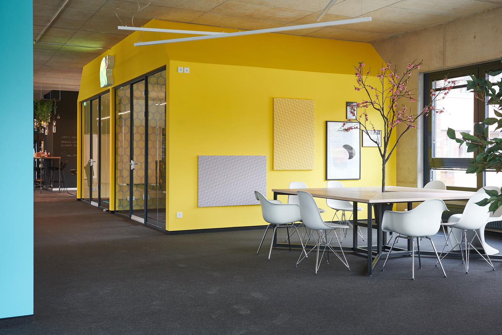 Headquarter einer Kita - Tisch aus der Cramer Holzmanufaktur, Stühle von Vitra, Bilder an der Wand: Canvas von Nya Nordiska und Urban Art
