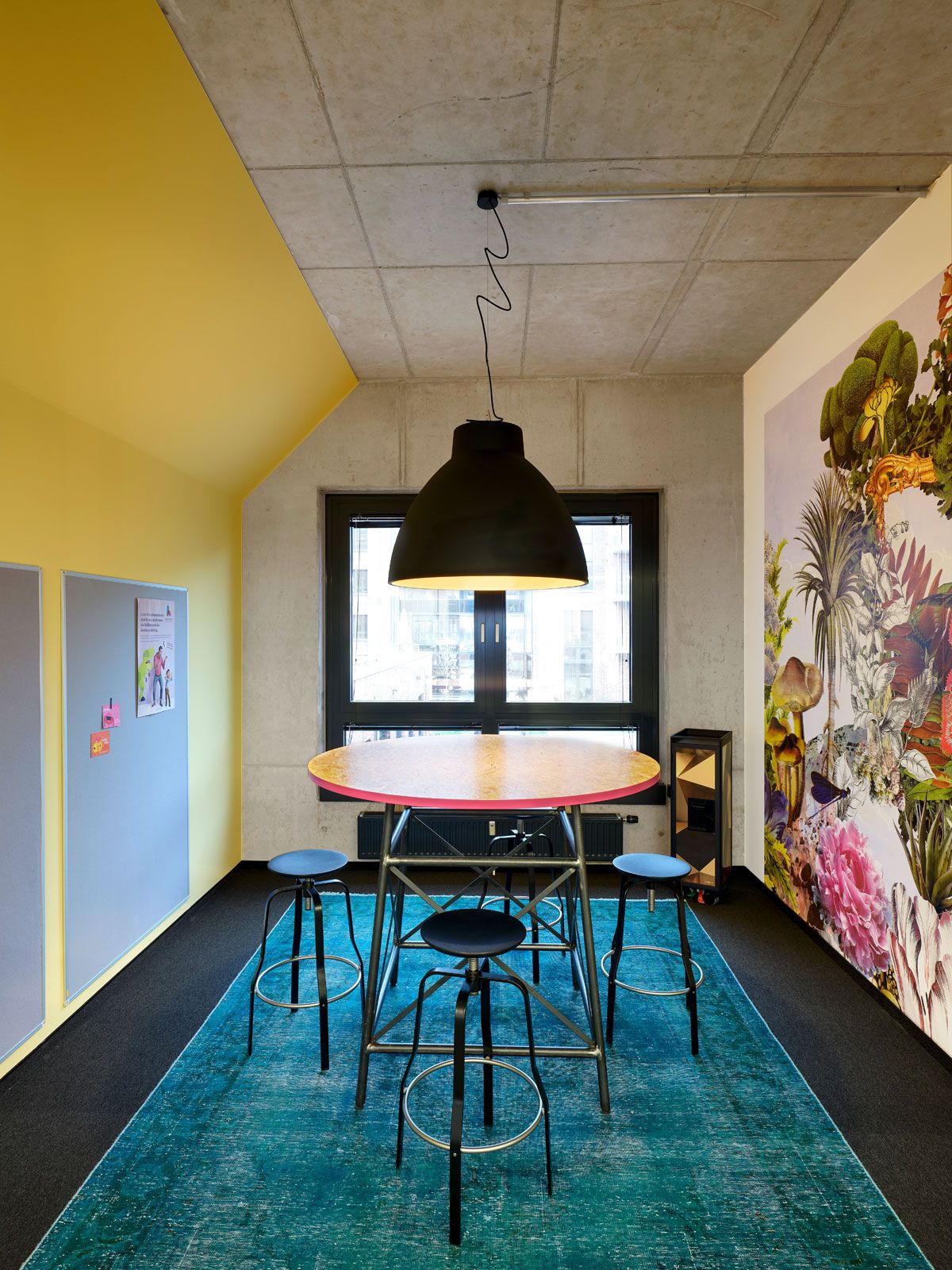 Headquarter einer Kita - Hocker Giro von Lapalma, Tisch aus der Cramer Holzmanufaktur, Pendelleuchte von Wever & Ducre, Tapete von Designers Guild, Teppich Vintage, Trolley von Bordbar