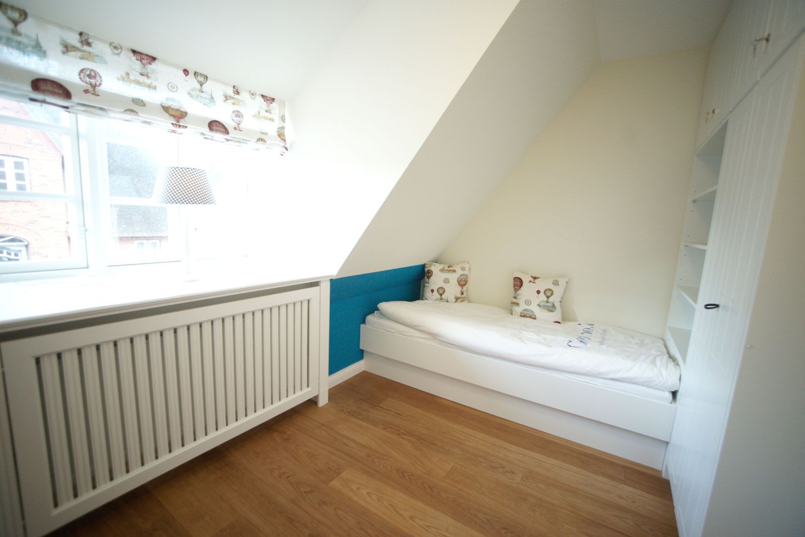 Ferienhaus auf Föhr - Kinderzimmer: Bett und Einbauschrank mit Regal aus der Cramer Holzmanufaktur