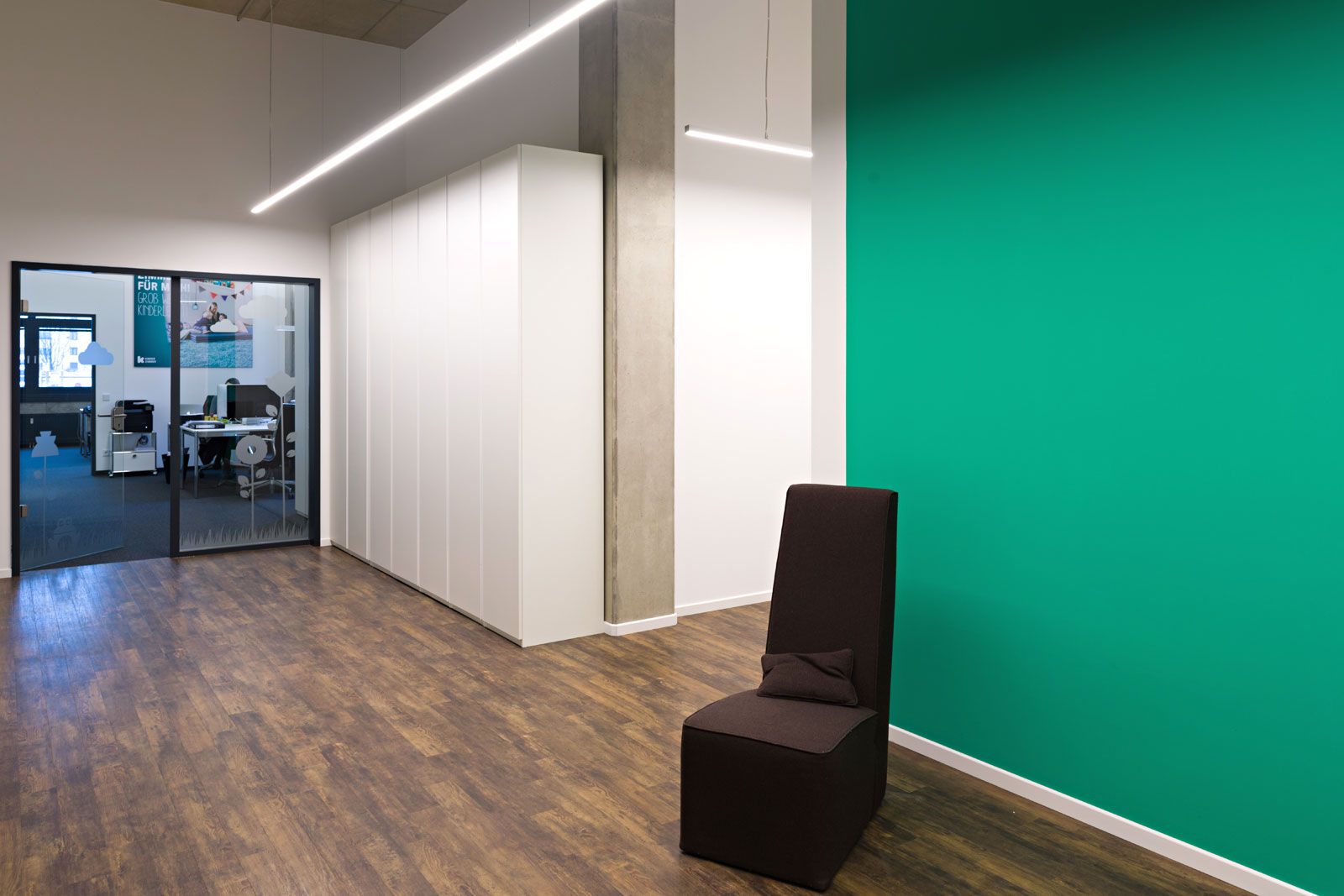 Headquarter im Industrial-Style - Sessel Vienna von Baxter, weißer Schrank aus der Cramer Holzmanufaktur, Pendelleuchte Ride von Molto Luce