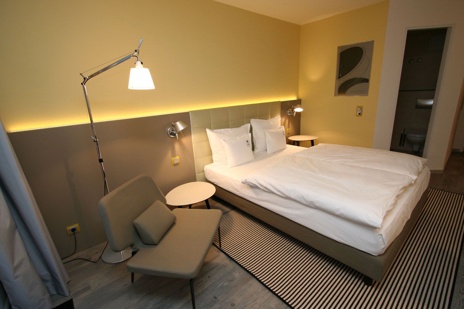 Boutique-Hotel an der Ostsee - Zimmerbeispiel: Beistellsessel Werner von Lema, Betthaupt als Sonderanfertigung von Lema, Nachttisch Flowers von Lema, Steh- und Wandleuchte Tolomeo von Artemide, Teppich von Object Carpet