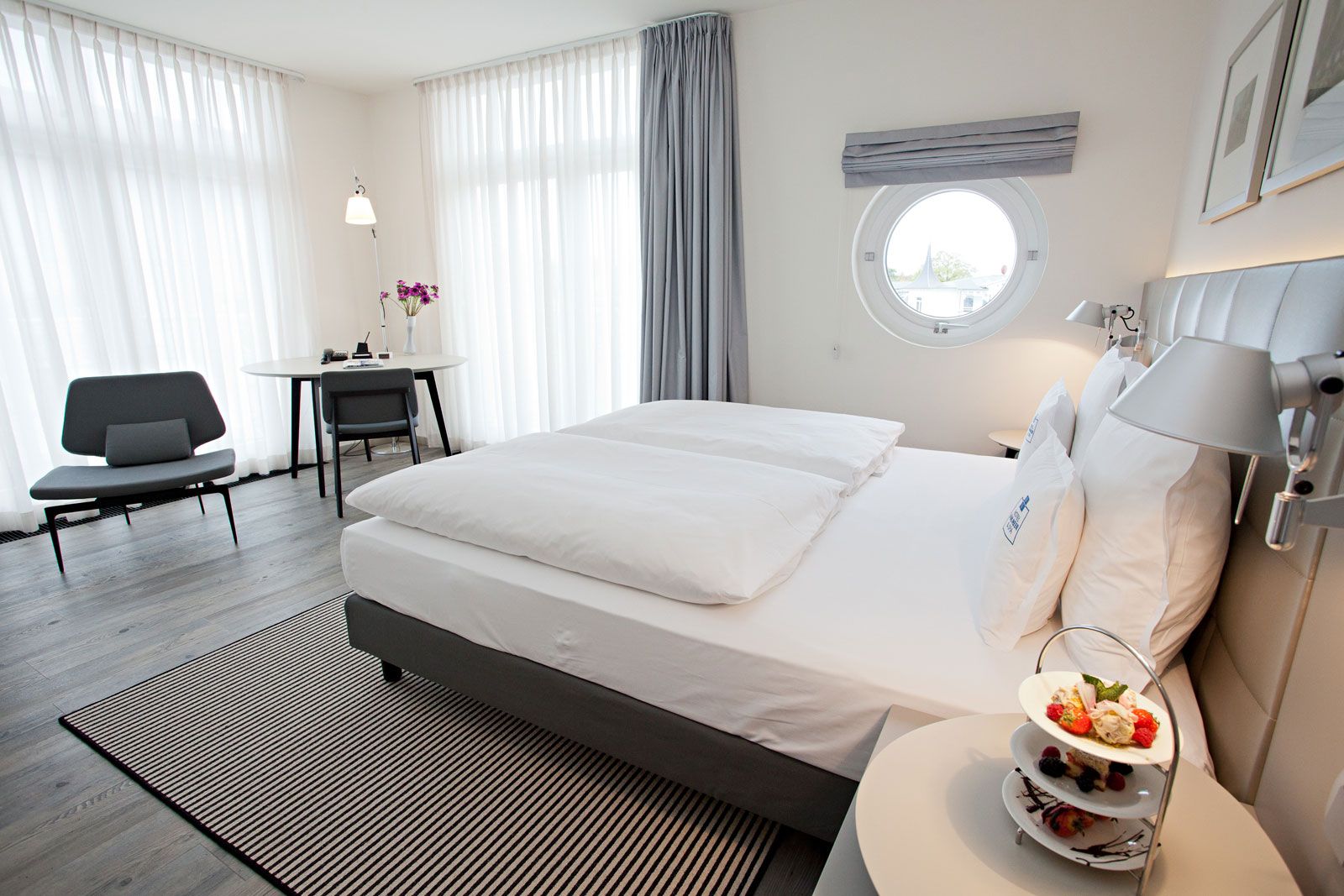 Boutique-Hotel an der Ostsee - Zimmerbeispiel: Werner Beistellsessel von Lema, Betthaupt als Sonderanfertigung von Lema, Steh- und Wandleuchte Tolomeo von Artemide, Teppich von Object Carpet