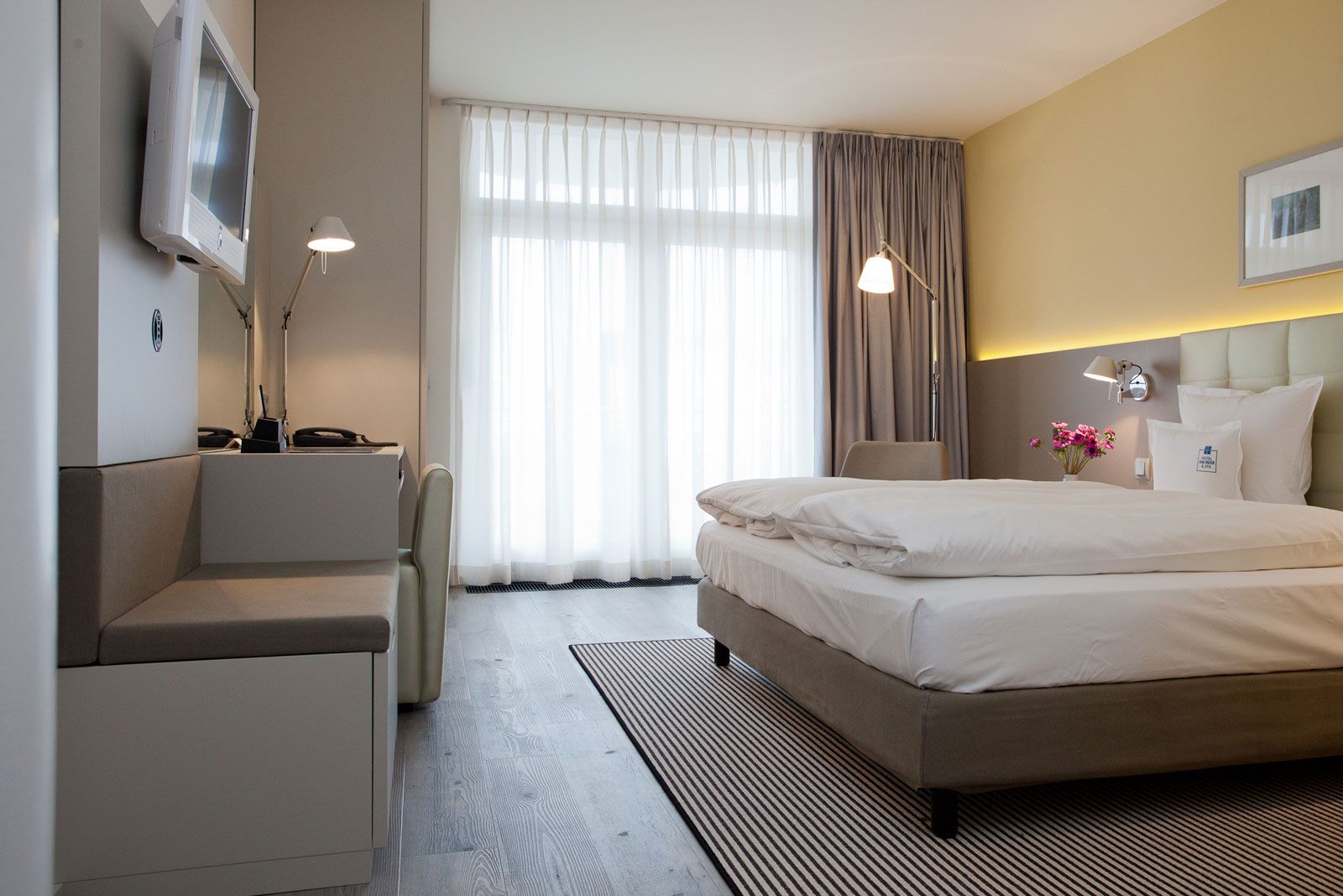 Boutique-Hotel an der Ostsee - Zimmerbeispiel: Sitzbank und Betthaupt als Sonderanfertigung von Lema, Steh- und Wandleuchte Tolomeo von Artemide, Teppich von Object Carpet