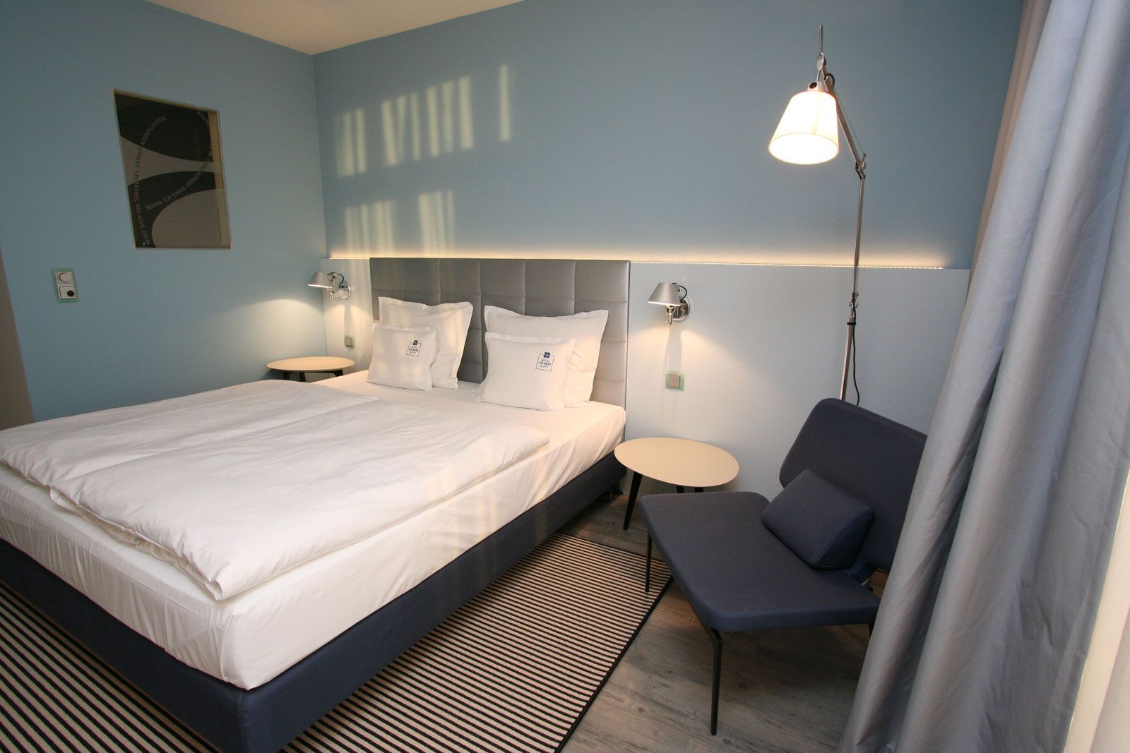 Boutique-Hotel an der Ostsee - Zimmerbeispiel: Beistellsessel Werner von Lema, Betthaupt als Sonderanfertigung von Lema, Nachttisch Flowers von Lema, Steh- und Wandleuchte Tolomeo von Artemide, Teppich von Object Carpet