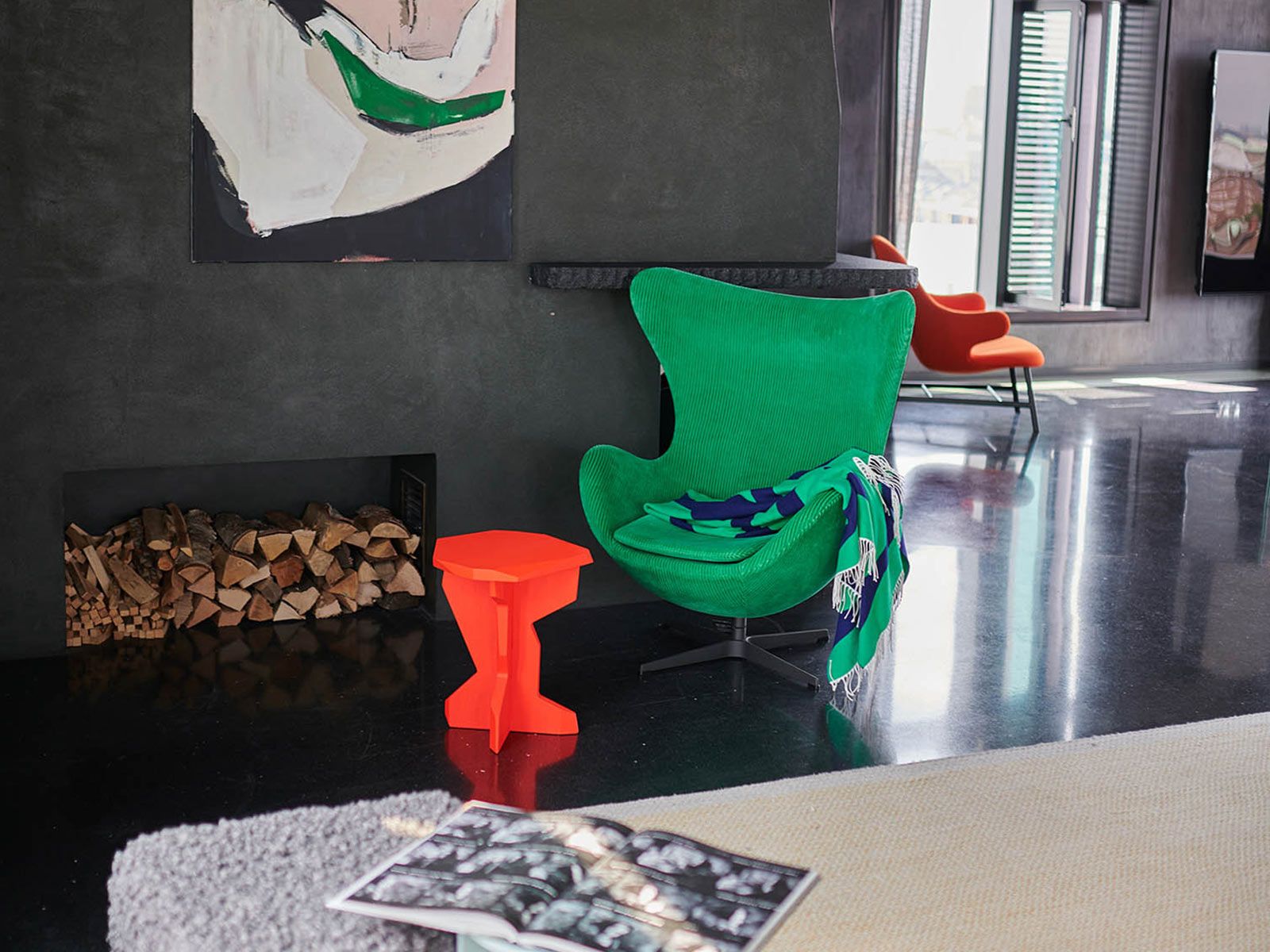 Loft in der Hafen City - Der grasgrüne Egg Chair von Fritz Hansen kombiniert mit dem neonfarbenen Fels Hocker von OUT lädt zum Relaxen neben dem Kamin ein.